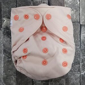 Pink cloth diaper with orange snaps, eco-friendly baby nappy, reusable diaper for babies.